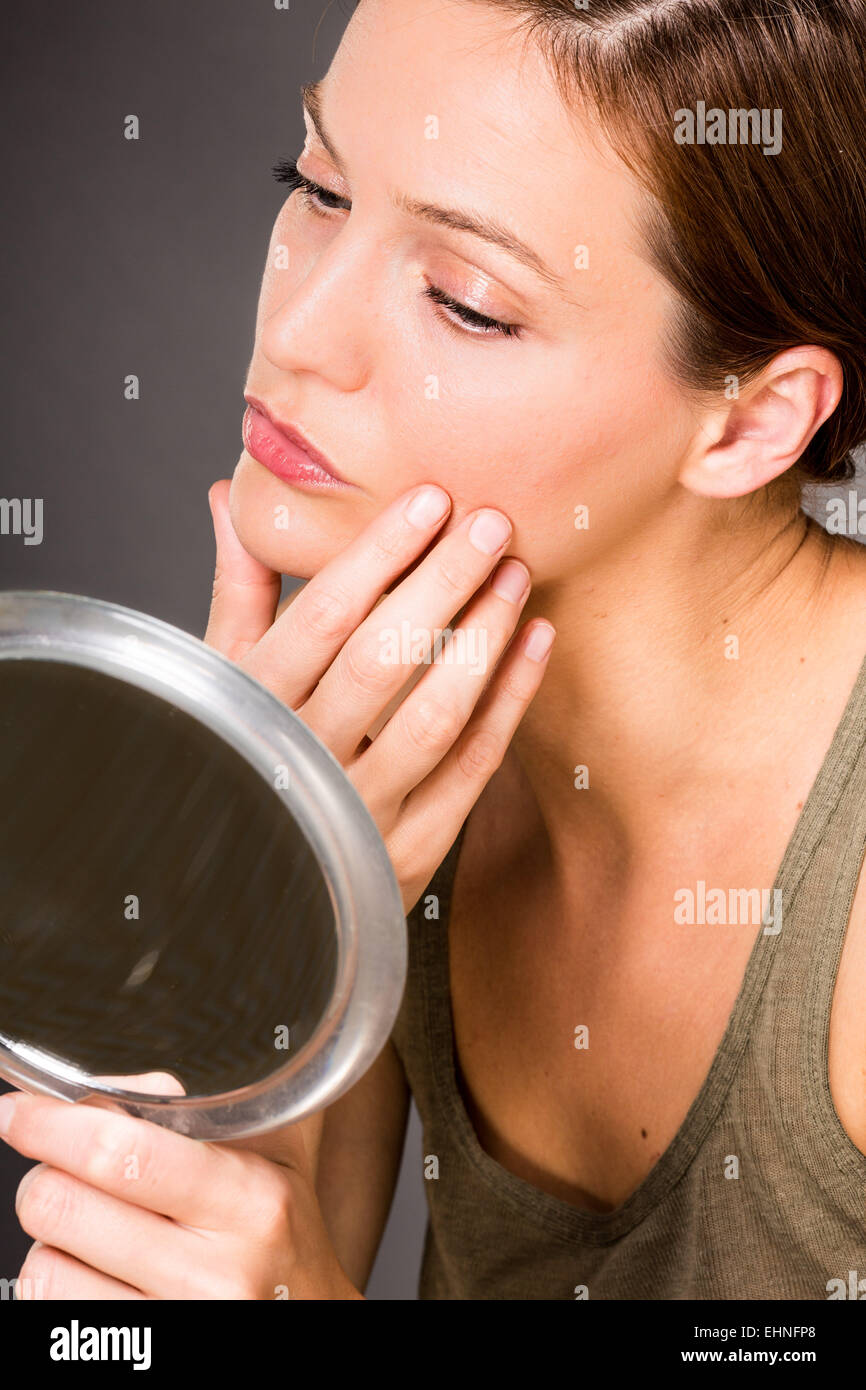 Frau ihr Gesicht im Spiegel zu überprüfen. Stockfoto