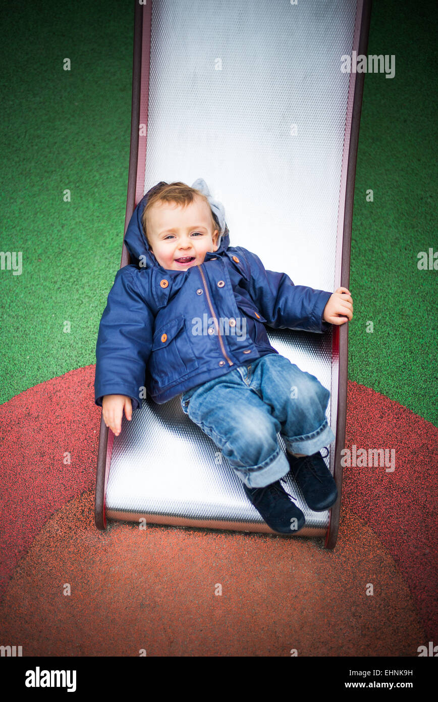 18 Monate altes Baby junge auf einer Folie auf einem Spielplatz. Stockfoto