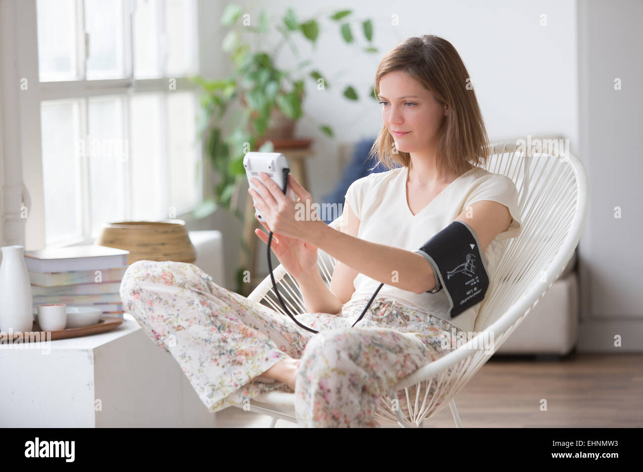 Frau, die ihren Blutdruck mit ein tragbares Blutdruckmessgerät. Stockfoto