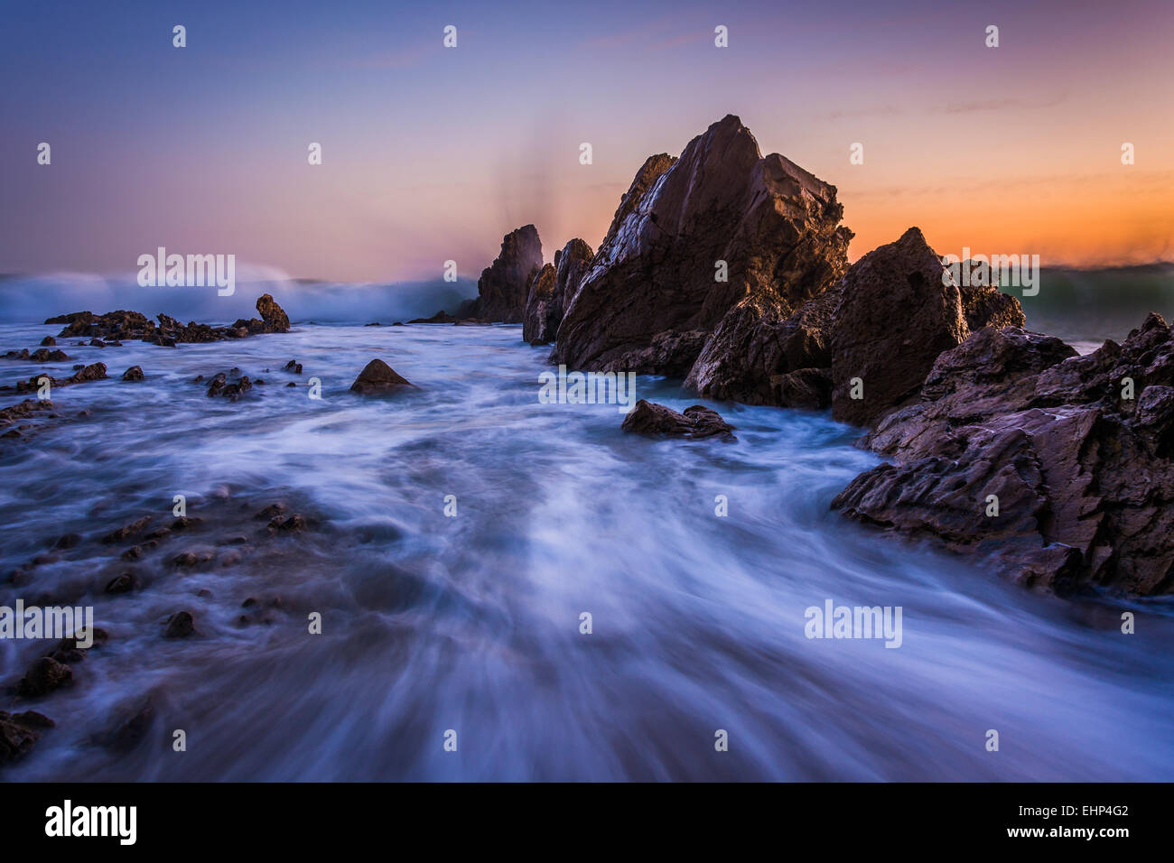 Wellen auf den Felsen bei Sonnenuntergang in Corona del Mar, California. Stockfoto