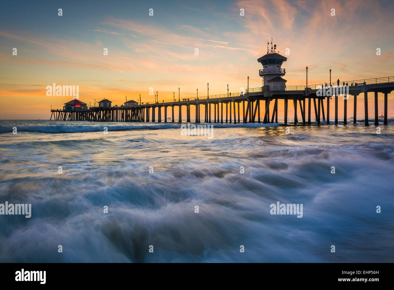 Wellen in den Pazifischen Ozean und der Mole bei Sonnenuntergang in Huntington Beach, Kalifornien. Stockfoto