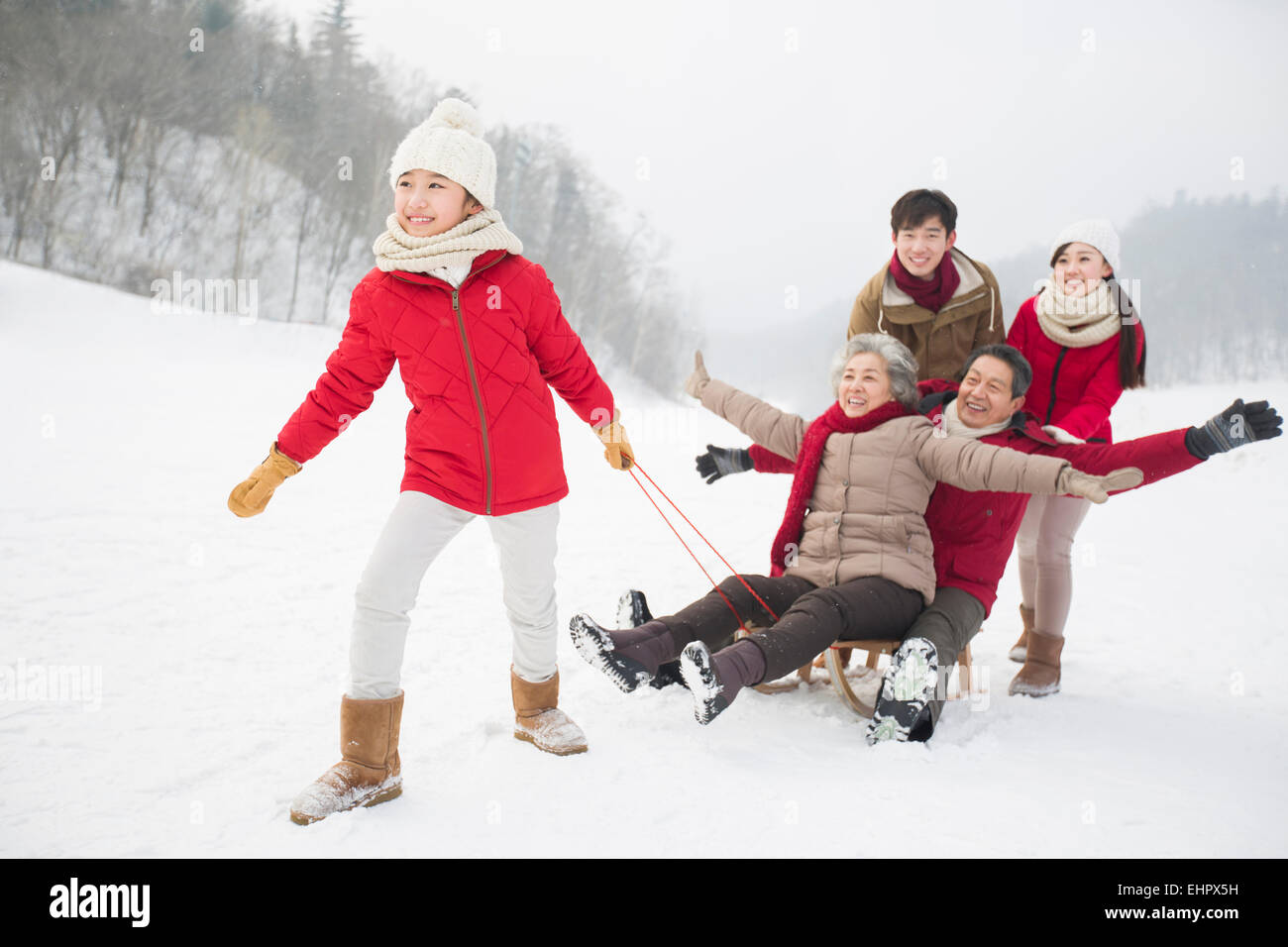 Glückliche Familie mit Schlitten im Schnee spielen Stockfoto