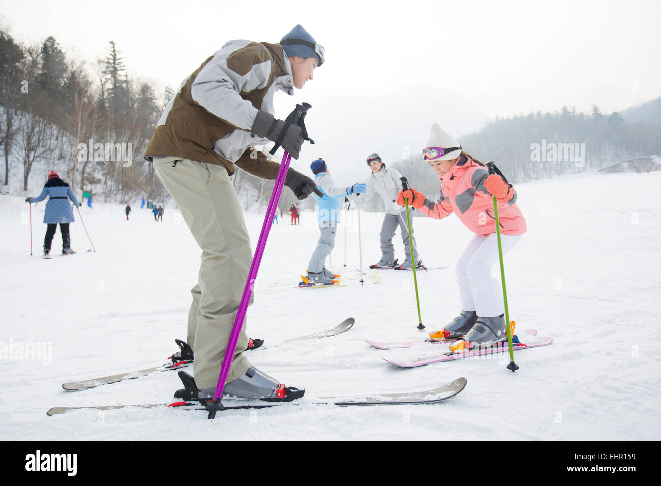 Junge Eltern, die Erziehung von Kindern zum Skifahren Stockfoto