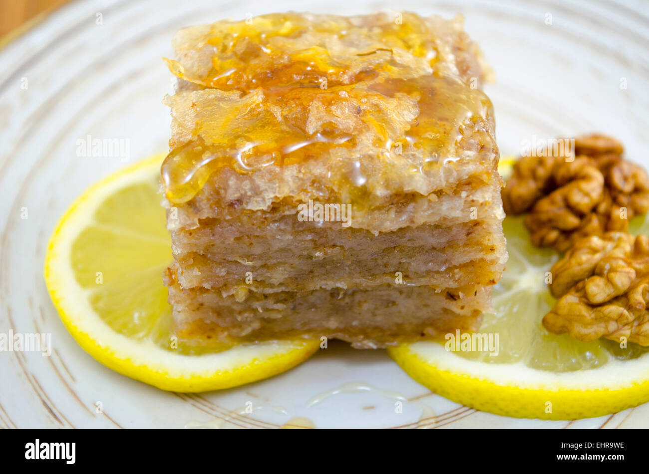 Saftige Baklava auf einem Teller, dekoriert mit Zitrone und Walnüssen, bereit, gegessen zu werden Stockfoto