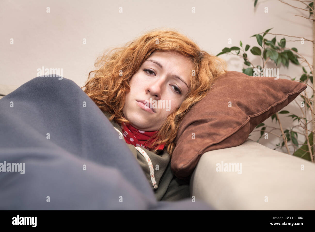 Unglücklich müde rothaarige Frau ruht auf dem Sofa zu Hause. Stockfoto