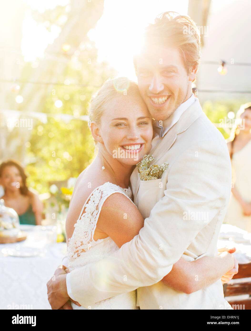 Porträt des jungen Paares umarmen im Garten während der Hochzeitsfeier Stockfoto