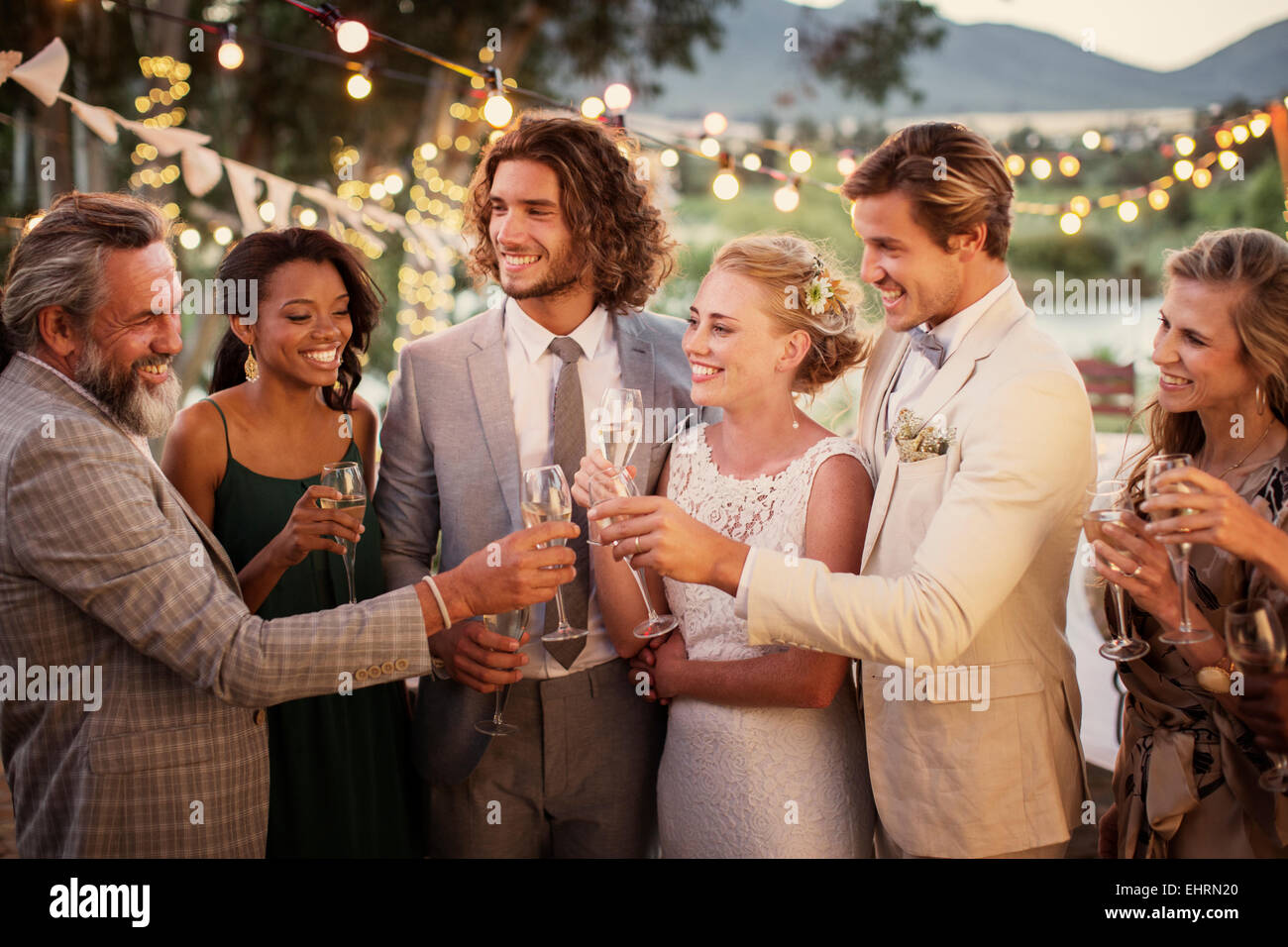 Junges Paar und ihre Gäste mit Sektgläser während Hochzeitsfeier im Garten Stockfoto
