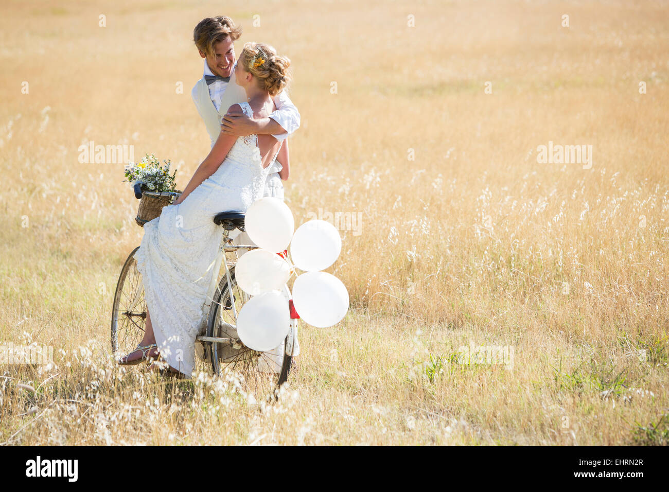 Braut und Bräutigam Reiten Fahrrad mit Ballons befestigt Stockfoto