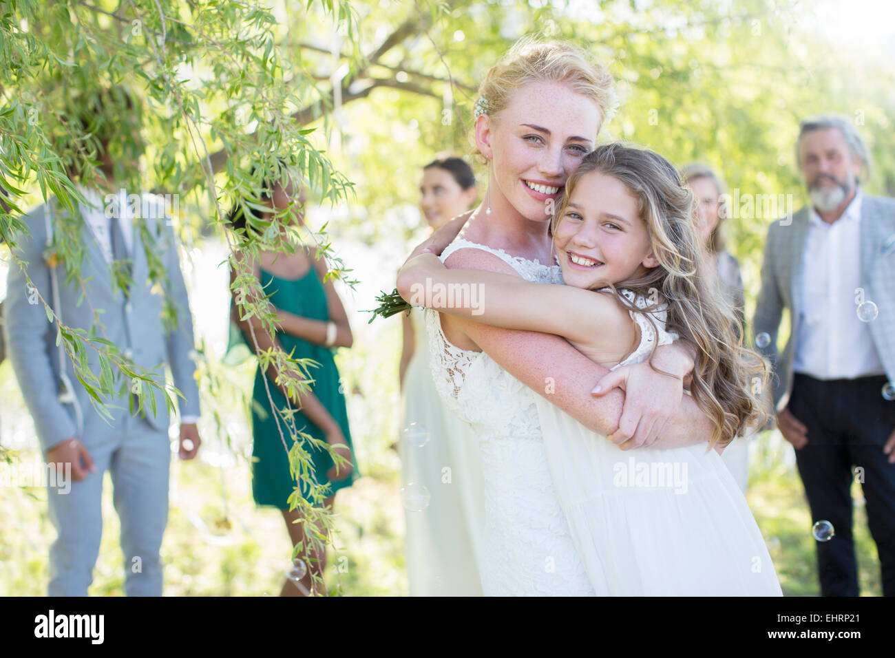 Braut umarmen Brautjungfer bei Hochzeitsfeier im heimischen Garten Stockfoto