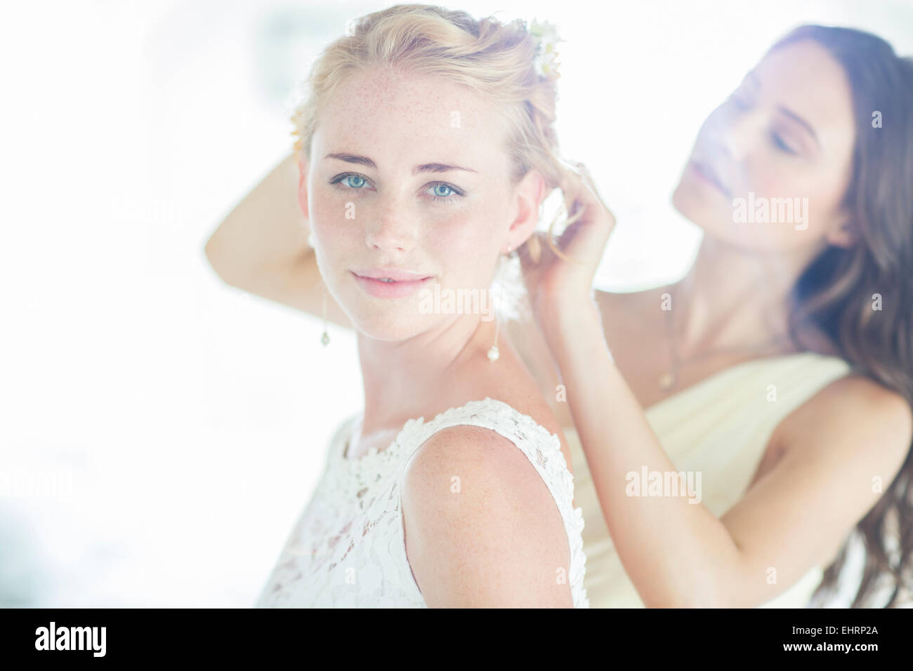Brautjungfer Braut mit Frisur im Wohnraum zu helfen Stockfoto