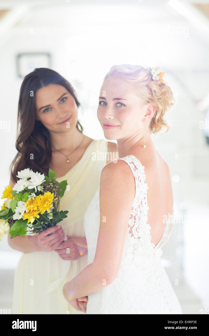 Porträt von Braut und Brautjungfer mit Blumenstrauß im Wohnraum Stockfoto