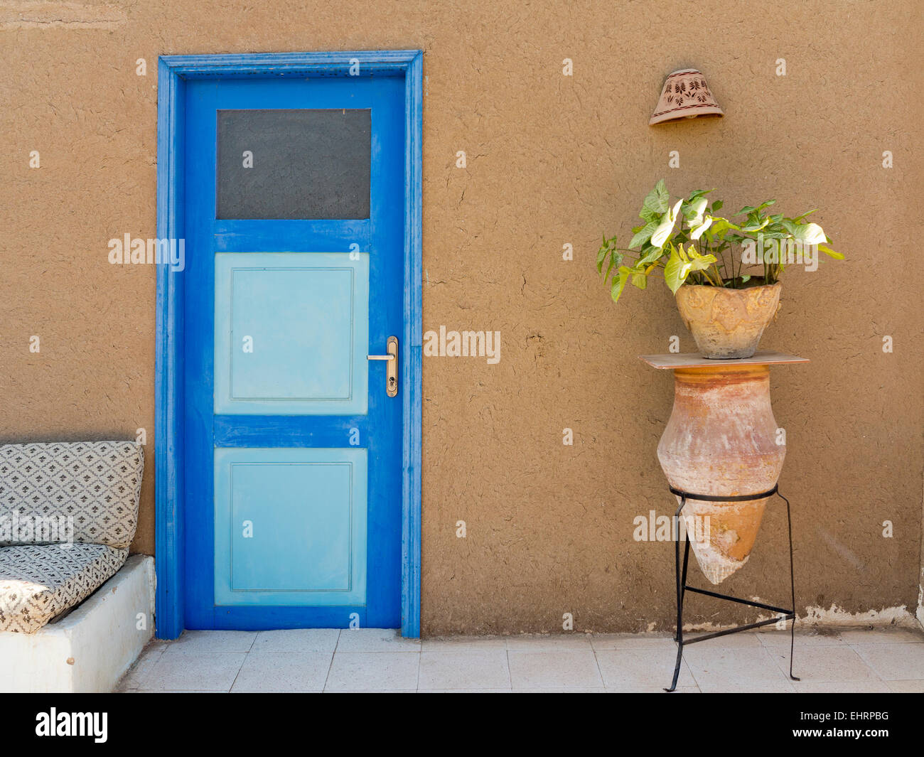 1 Keramik-Wasserträger am Stativ Metallständer als ein Werk stehen gegen eine helle blaue Tür & Schlamm Mauer Ägypten Afrika Stockfoto