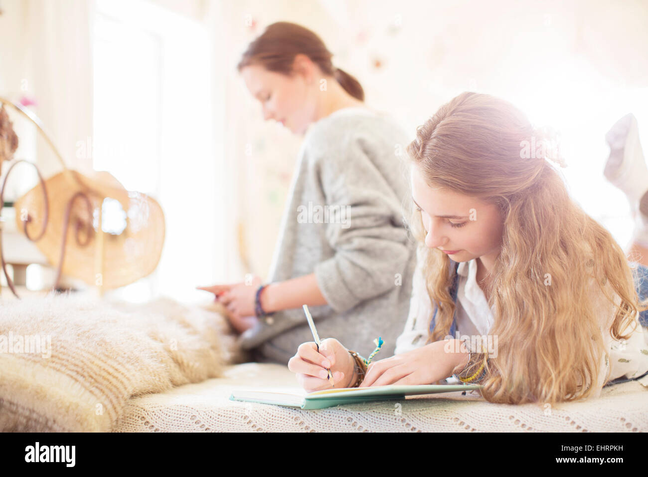 Zwei Mädchen im Teenageralter auf Bett schriftlich Notizblöcke Stockfoto