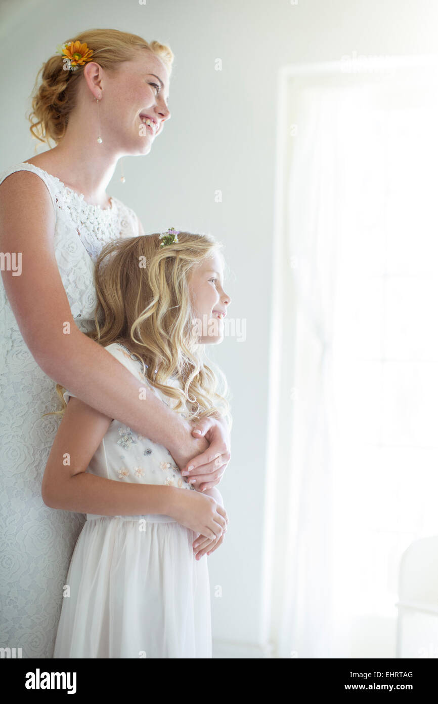 Braut umarmen Brautjungfer und Blick aus Fenster Stockfoto