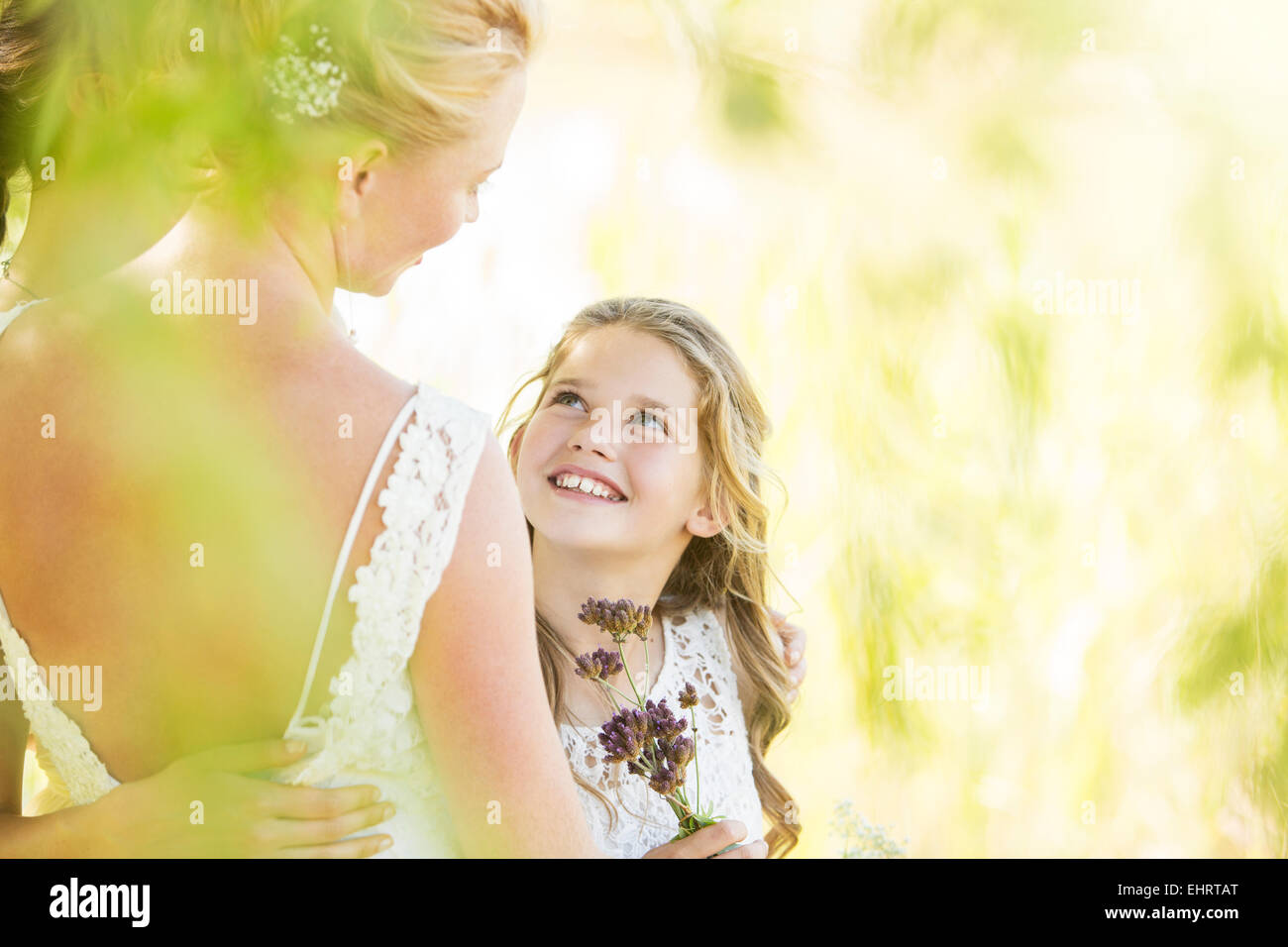 Lächelnde Brautjungfer mit Blumen und Braut während der Hochzeitsfeier im Garten Stockfoto