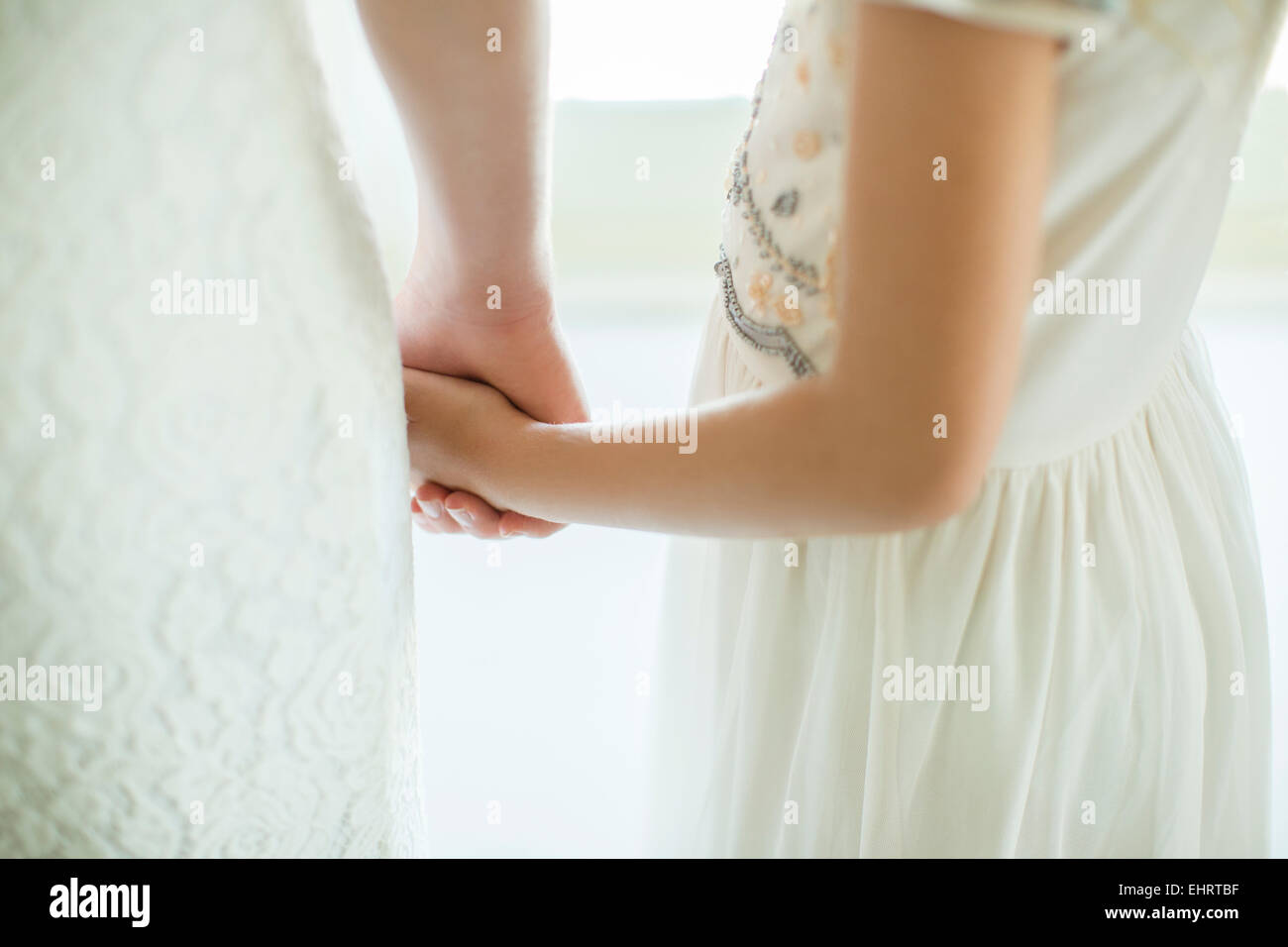 Braut hält Brautjungfer Hand im Wohnraum Stockfoto