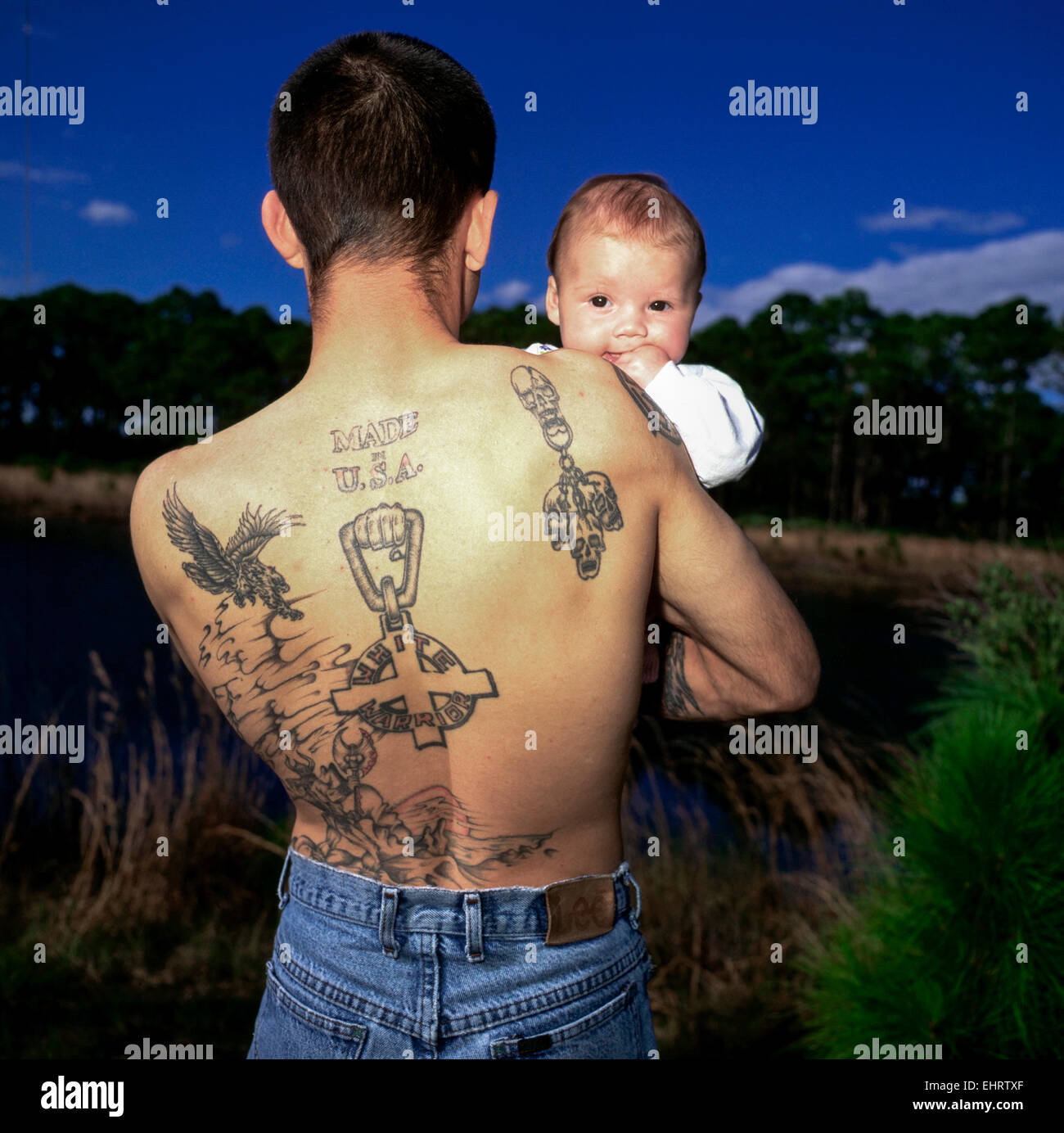 MELBOURNE, USA – März 1: Mann mit "weißer Krieger & made in USA" Tattoo halten Baby in der Nähe von Melbourne, Florida am 1. April 1996. Stockfoto