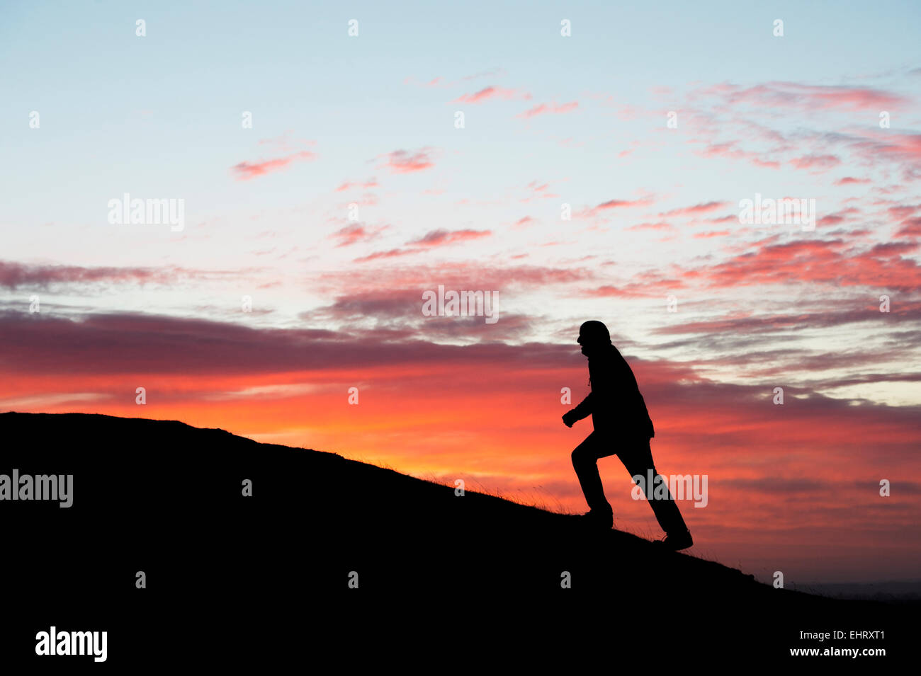 Mann zu Fuß auf einem Hügel bei Sonnenaufgang. Silhouette. UK Stockfoto