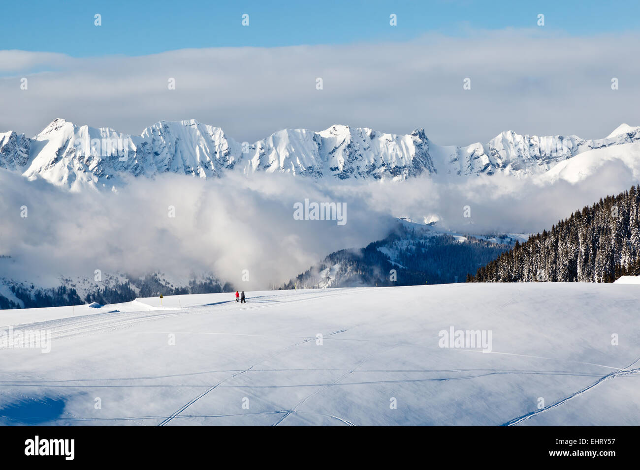 Panoramablick auf Berge und zwei Personen Trekking in Französische Alpen im Winter Stockfoto