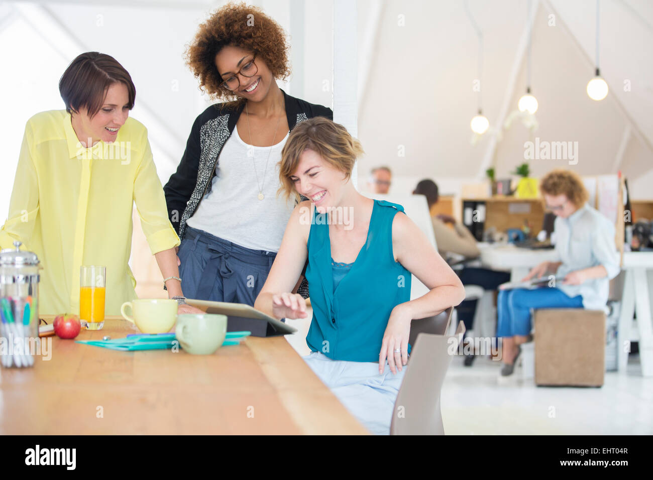 Frauen mit Blick auf digital-Tablette und lächelnd in Büro Stockfoto