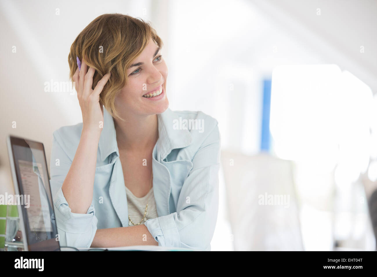 haltende Hand in den Haaren, Portrait Frau mit Laptop lächelnd Stockfoto