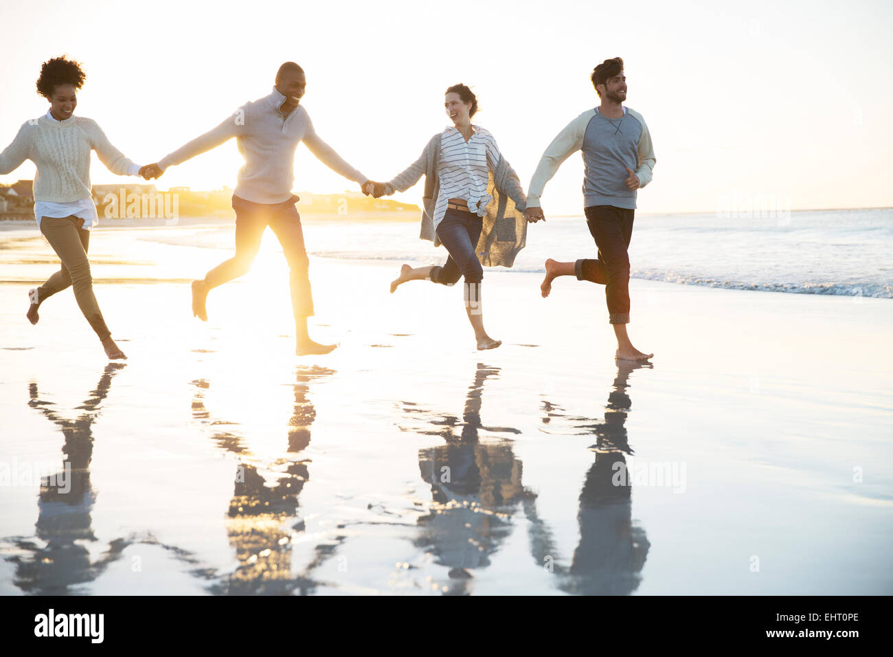 Gruppe von vier Freunden, Hand in Hand und laufen am Strand Stockfoto