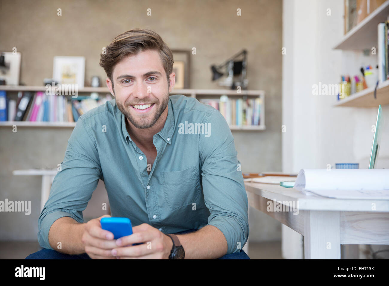 Porträt der junge blonde Mann, sitzend mit Mobiltelefon Stockfoto