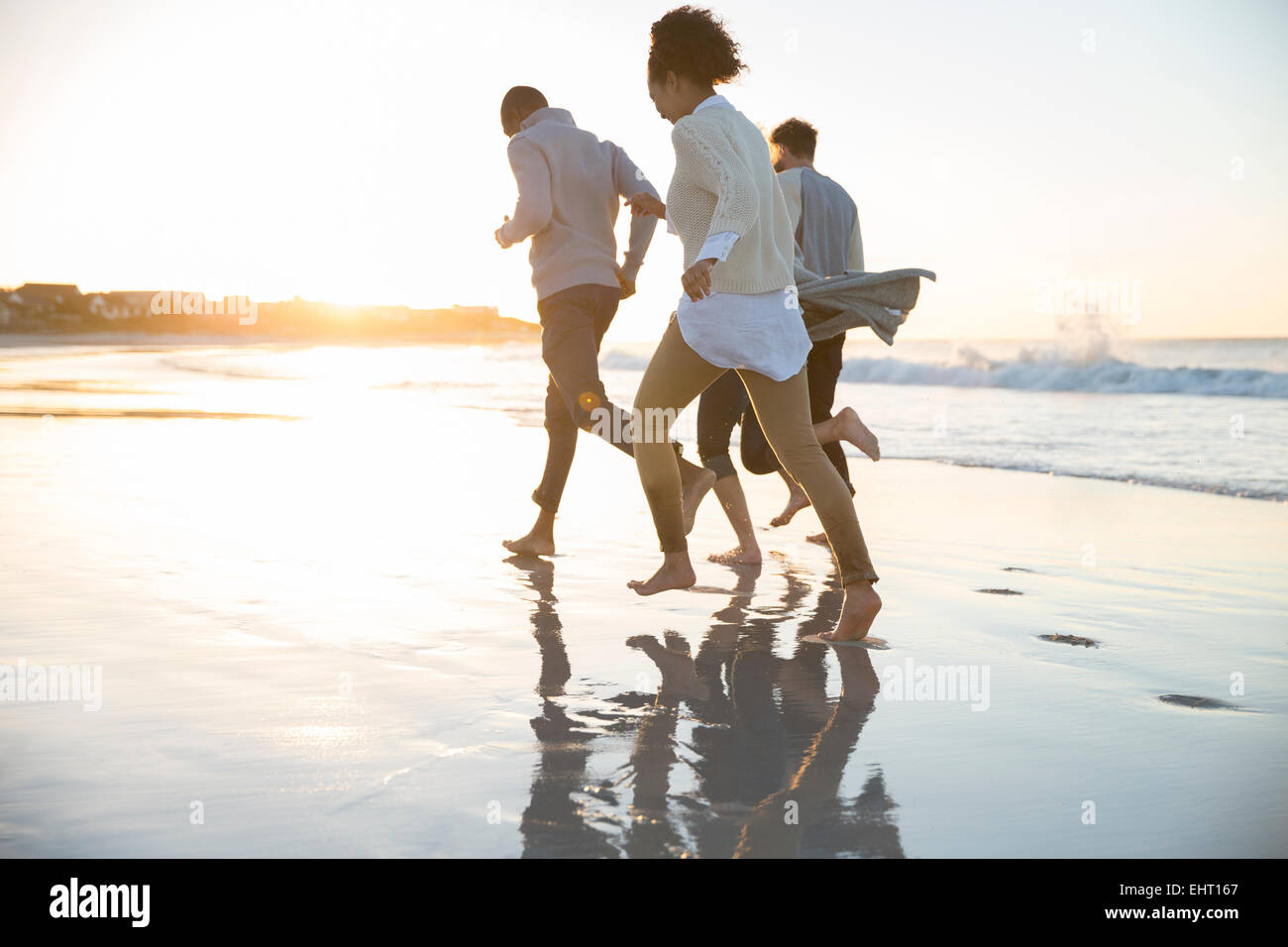 Vier Freunde laufen Ob Strand in Abendsonne Stockfoto