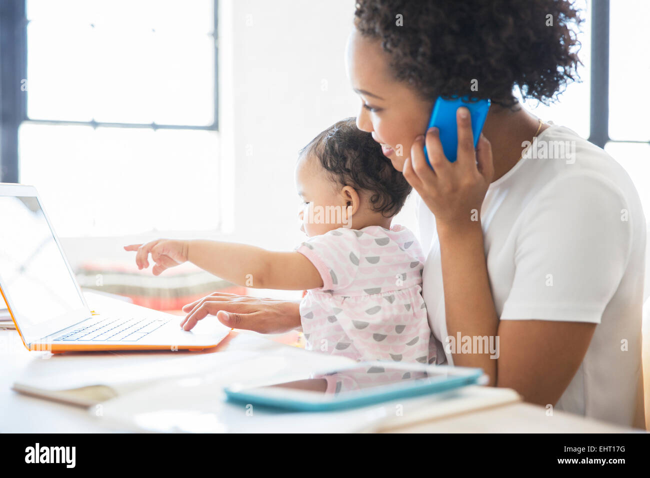 Mutter mit Tochter sitzt auf dem Schoß von zu Hause aus arbeiten Stockfoto