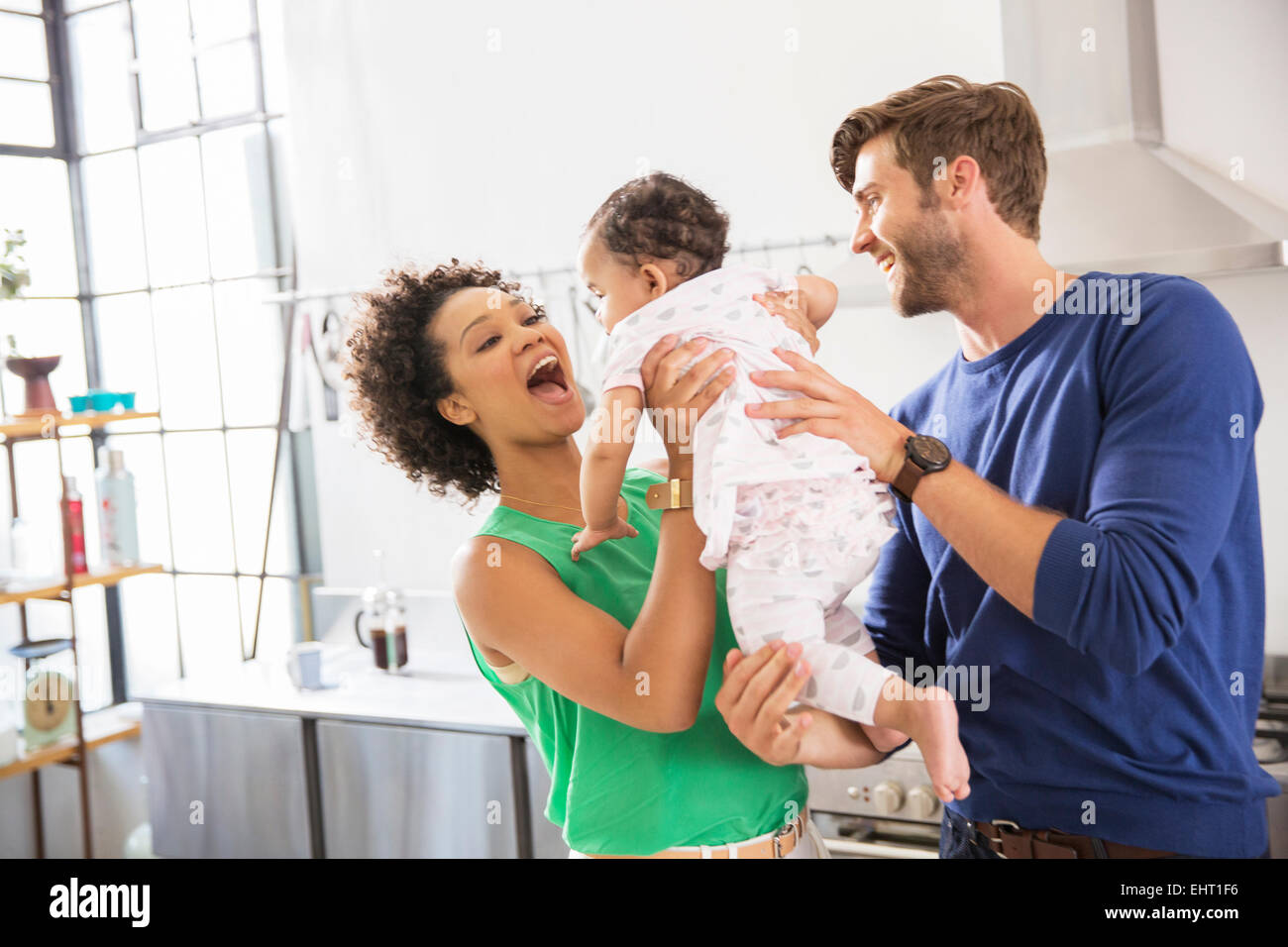 Glückliche Eltern halten ihre Tochter in der heimischen Küche Stockfoto