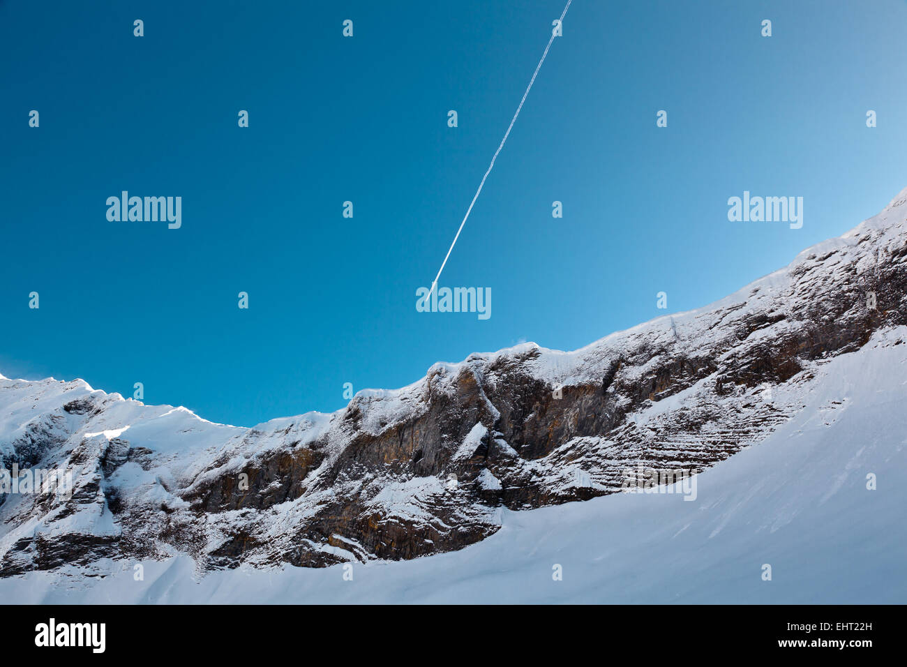 Flugzeug-Trail im blauen Himmel über Berggipfel, Französische Alpen Stockfoto
