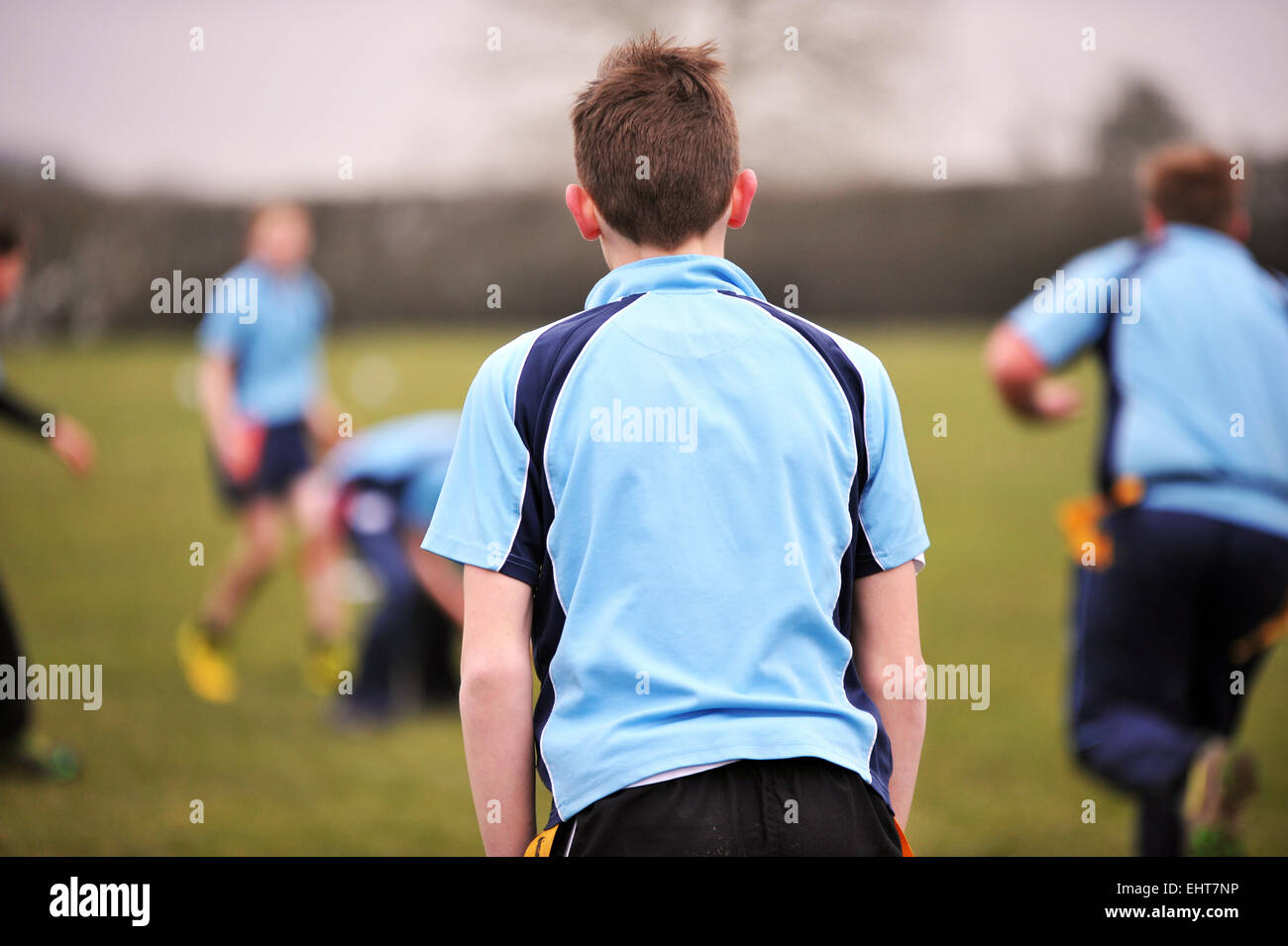 Junge schaut ein Rugby-Spiel von der Seitenlinie, Blick von der Rückseite. Stockfoto