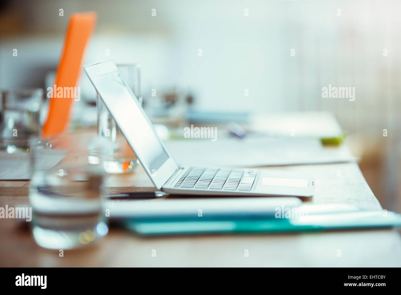 Bürobedarf, ein Laptop und ein Glas Wasser auf dem Schreibtisch im Büro Stockfoto