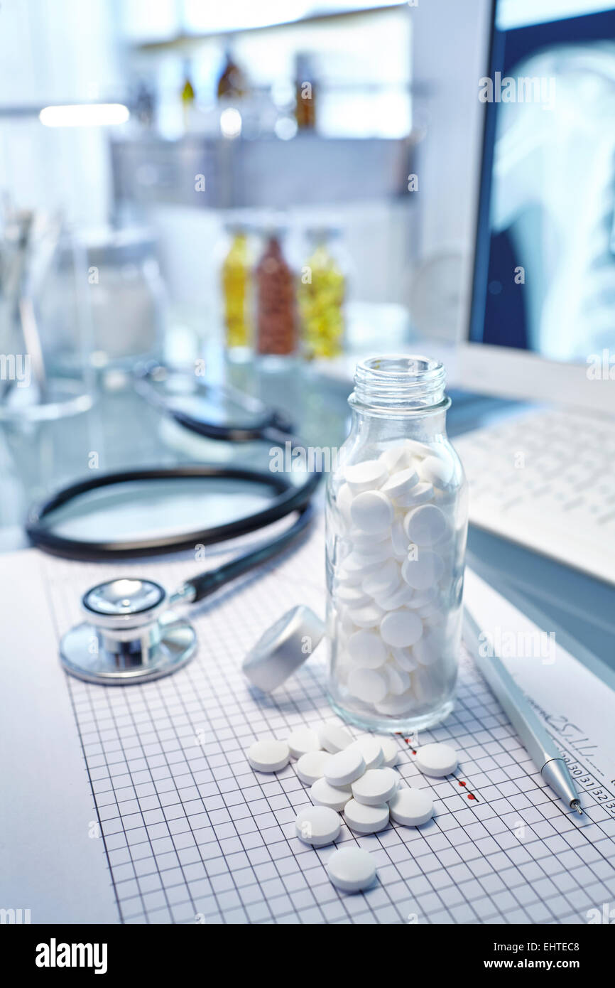 Kolben mit weißen Pillen, Diagramm und Stethoskop auf Schreibtisch Stockfoto