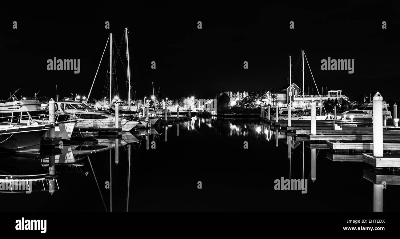 Boote und Docks spiegelt sich im Wasser in der Nacht, in einer Marina in Kent Island, Maryland Stockfoto