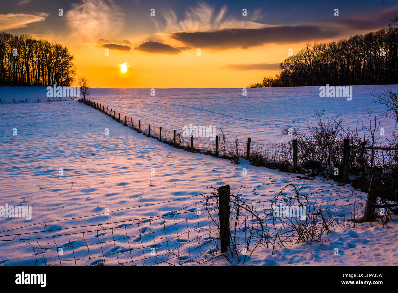 Sonnenuntergang über einen Zaun in ein Schnee bedeckt Feld-Hof in ländlichen Carroll County, Maryland. Stockfoto