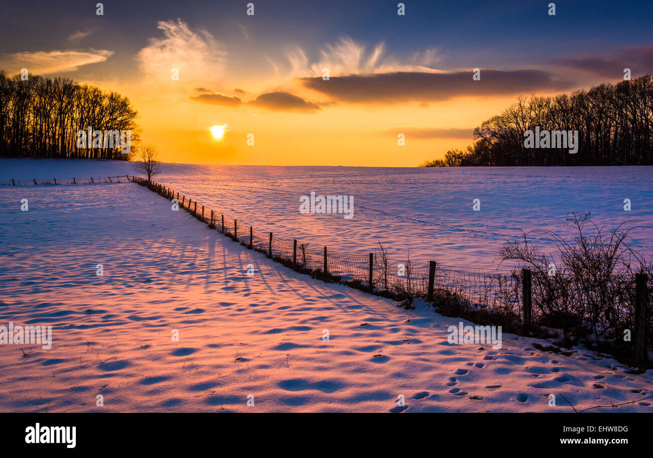 Sonnenuntergang über einen Zaun in ein Schnee bedeckt Feld-Hof in ländlichen Carroll County, Maryland. Stockfoto