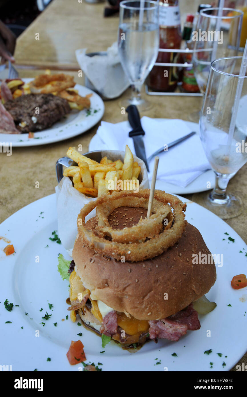 Gebratene Zwiebelringe auf großen gourmet Rindfleisch Hamburger mit Speck und Käse auf dem weißen Teller Stockfoto