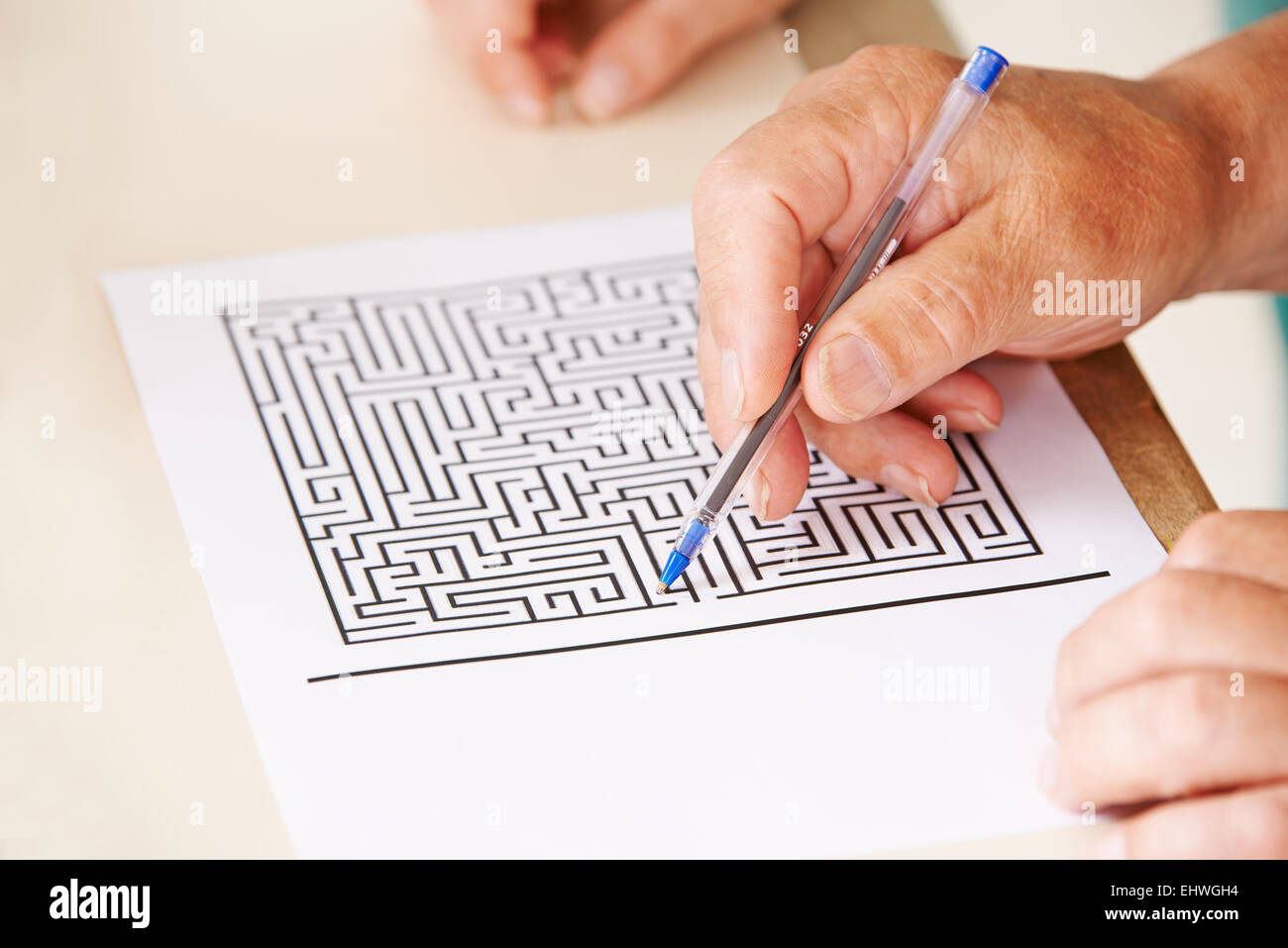 Hand der ältere Mann mit Stift tun der Gedächtnistraining mit einem Papier-Labyrinth Stockfoto