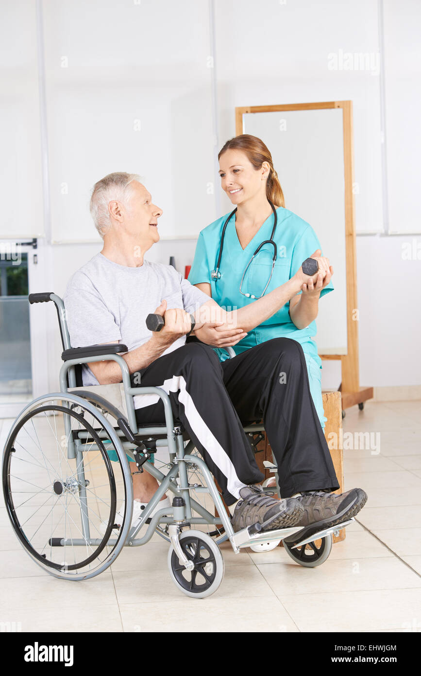 Ältere Mann im Rollstuhl heben Hanteln in der Physiotherapie Stockfoto