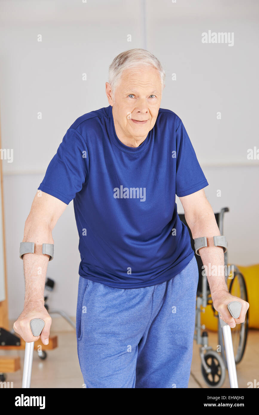 Alter Mann mit Krücken in der Reha nach einem Unfall laufen lernen Stockfoto