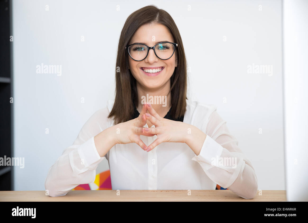 Glücklich Geschäftsfrau sitzt am Tisch im Büro Stockfoto