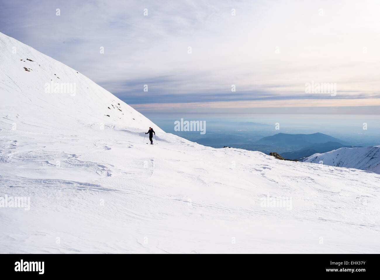 Land Skifahrer Wandern bergauf auf verschneiten Hang mit Panoramablick in den Hintergrund zurück. Konzept der Widrigkeiten zu erobern. Stockfoto