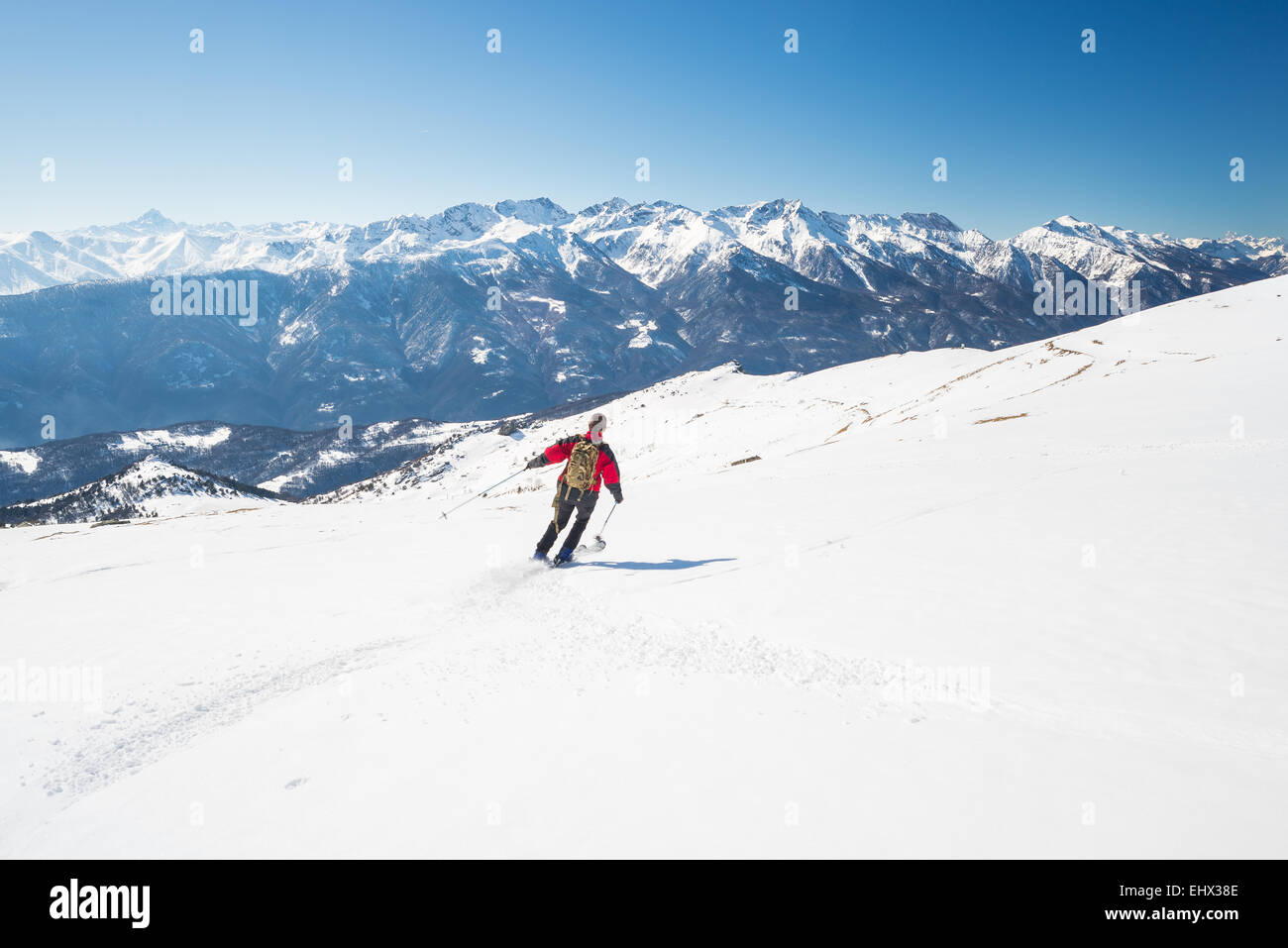 Eine Person, die Ski Abfahrten auf verschneiten Hang in malerische Skigebiet der Alpen, mit hellen, sonnigen Tag Ende Wintersaison Stockfoto