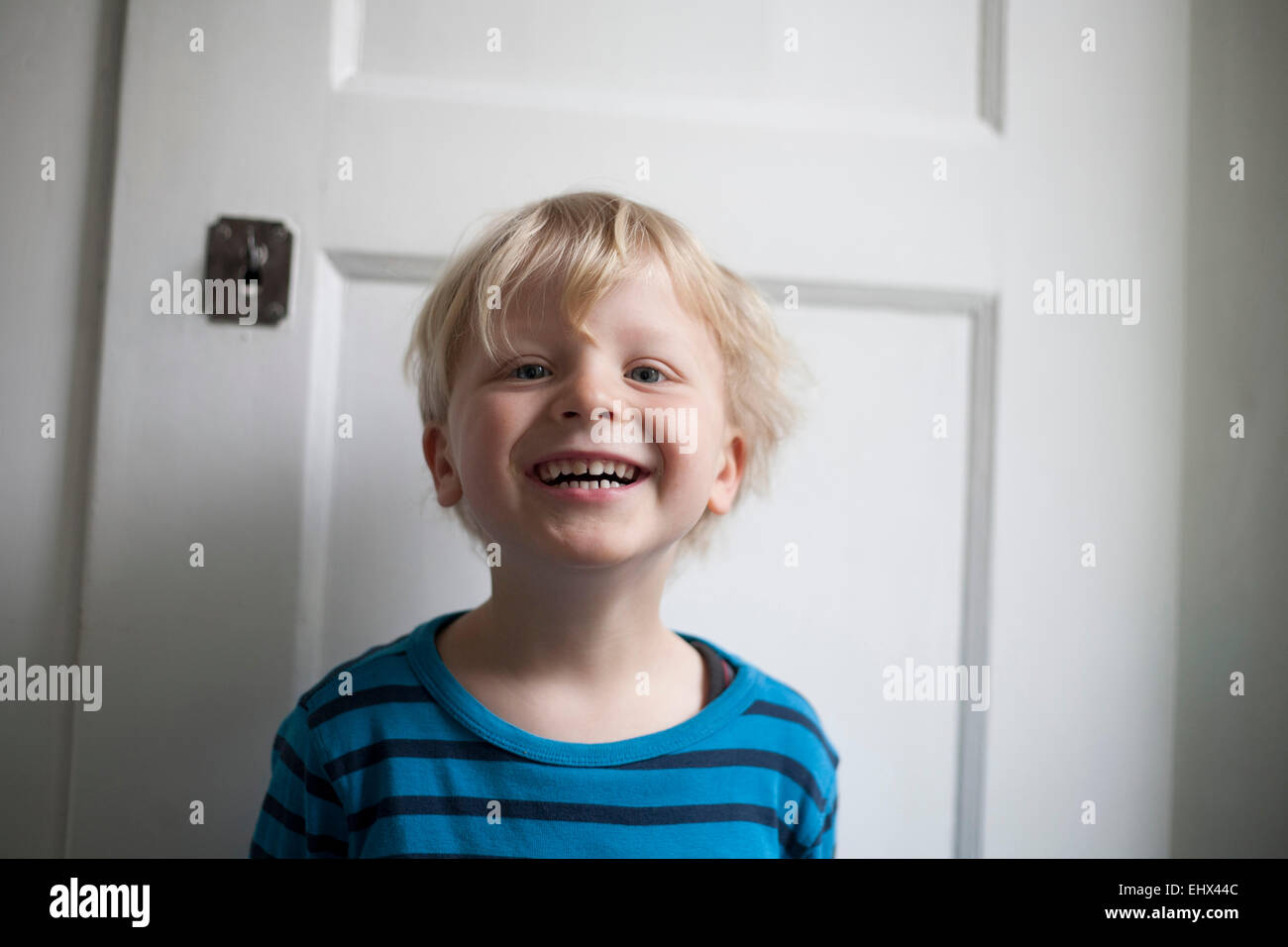Porträt des lachenden kleinen Jungen vor weiße Tür Stockfoto