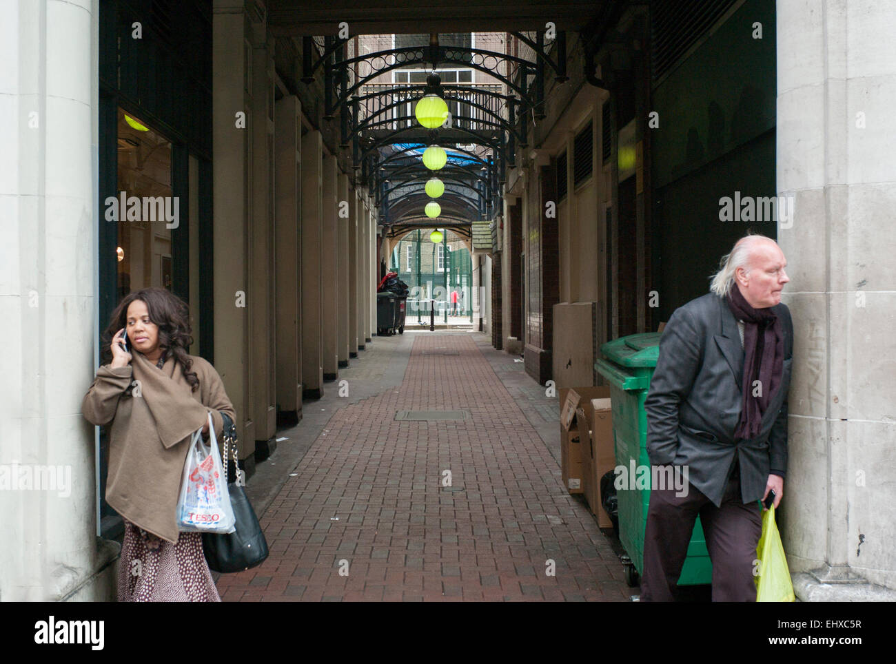 verfallene Einkaufspassage Tottenham court Road London asiatische Dame und weißer Mann in entgegengesetzte Richtungen suchen Stockfoto