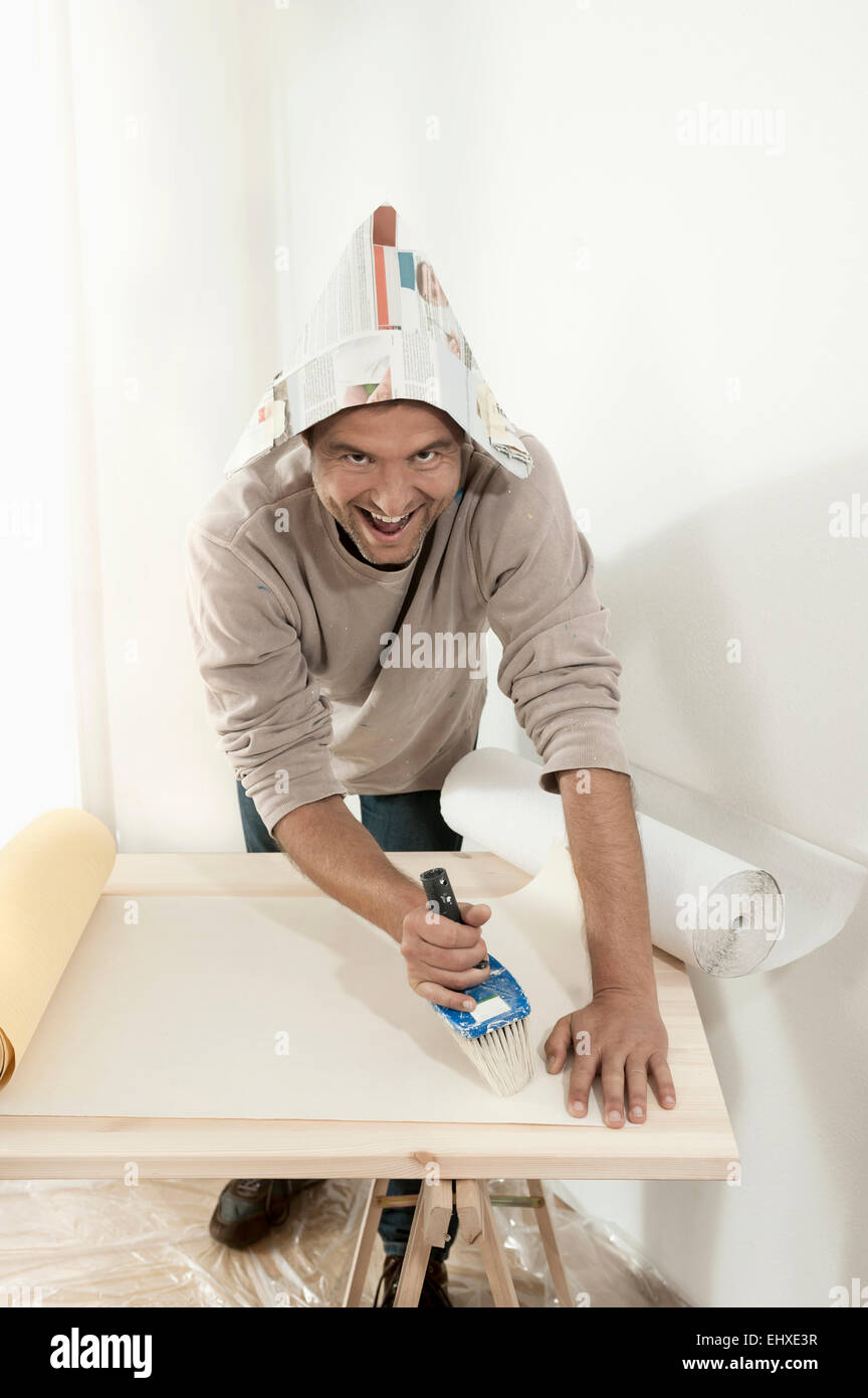 Mann mit Kleber auf Tapete mit einem Pinsel, Bayern, Deutschland Stockfoto