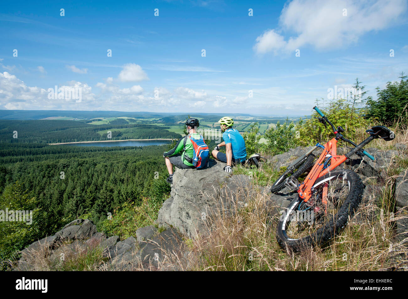 Mountainbiker, die entspannend auf Berg, Erzgebirge, Sachsen, Deutschland Stockfoto