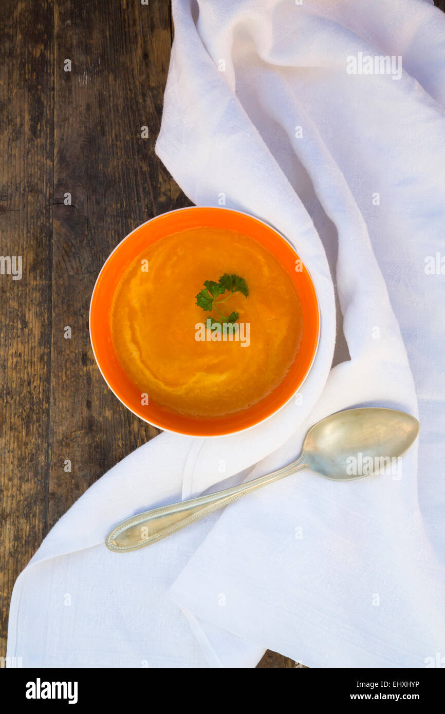 Schüssel mit Karottensuppe, Löffel und Serviette Stockfoto