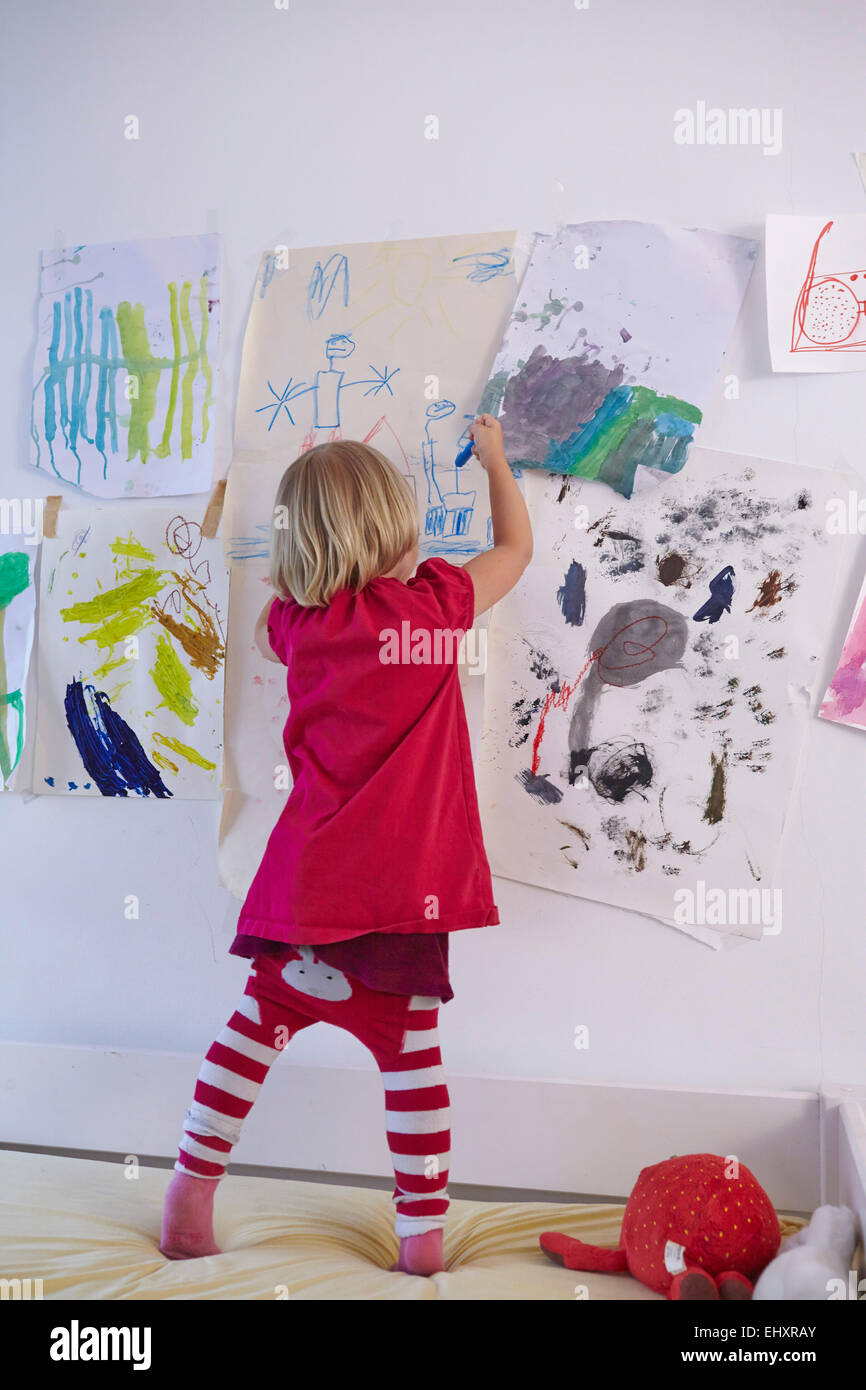 Kleines Mädchen malen an der Wand des Kinderzimmers, Rückansicht Stockfoto